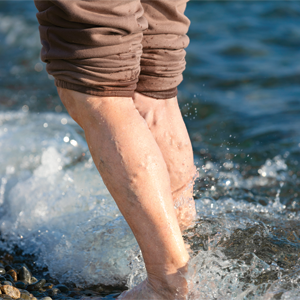 Person standing in the water with brown pants rolled up